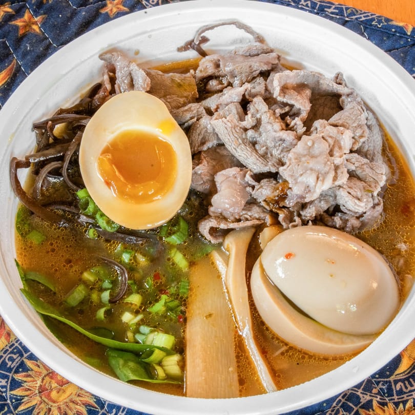 Rai Rai Ramen's beef ramen bowl with sliced meat, soft-boiled eggs, green onions, and mushrooms.