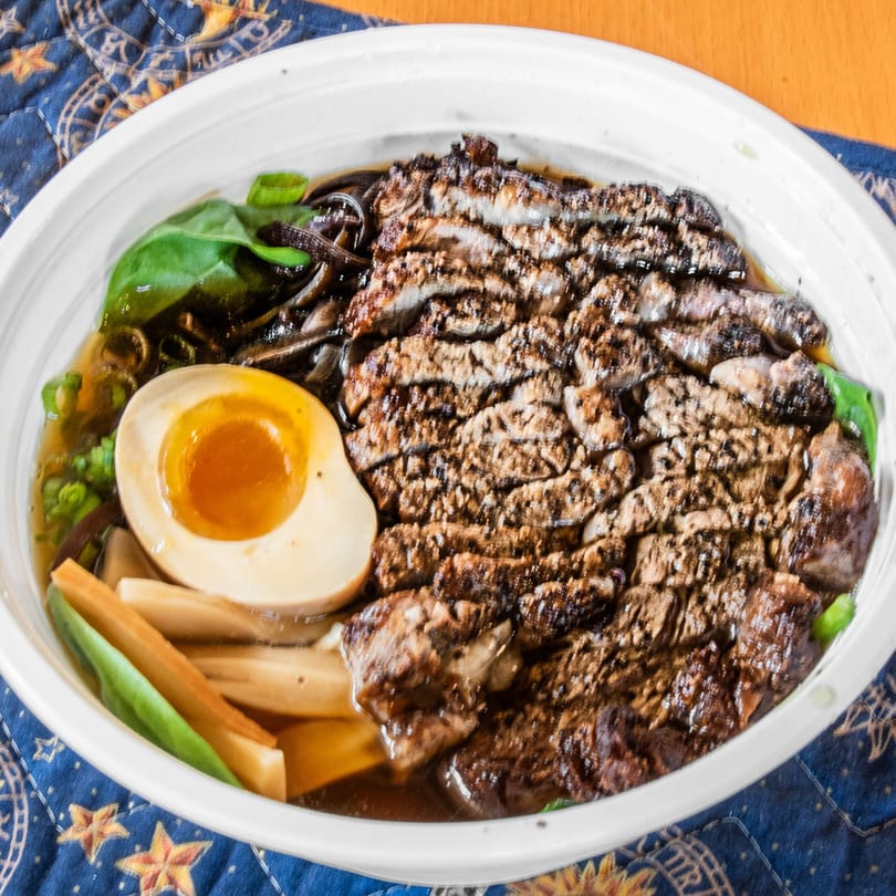Rai Rai Ramen's ramen bowl with sliced meat, a soft-boiled egg, and vegetables.